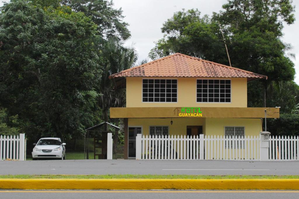 un'auto parcheggiata di fronte a un edificio giallo di Hostel Guayacan a Puerto Armuelles