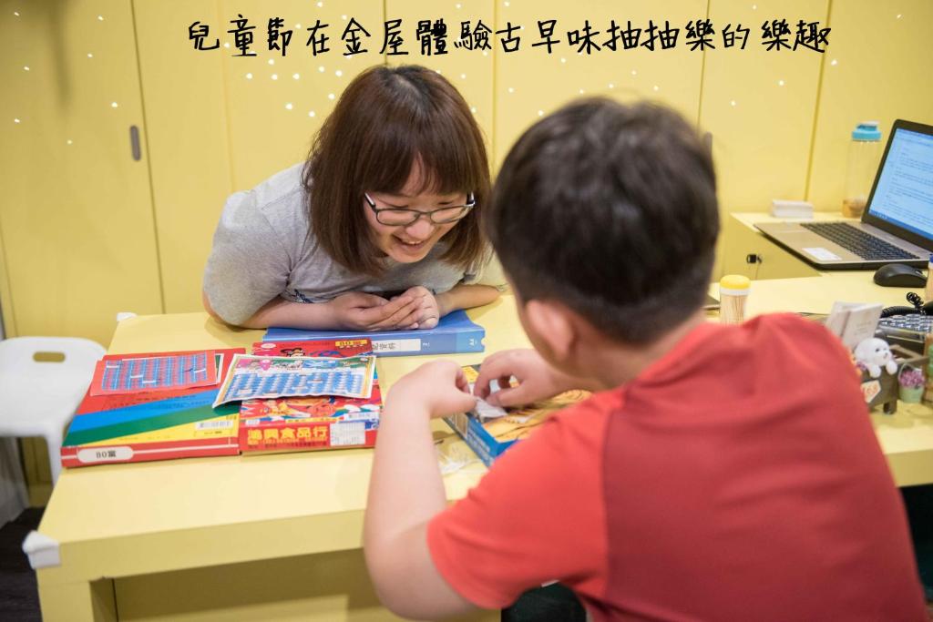 un niño y una mujer sentados en una mesa con libros en King Wow Inn, en Tainan