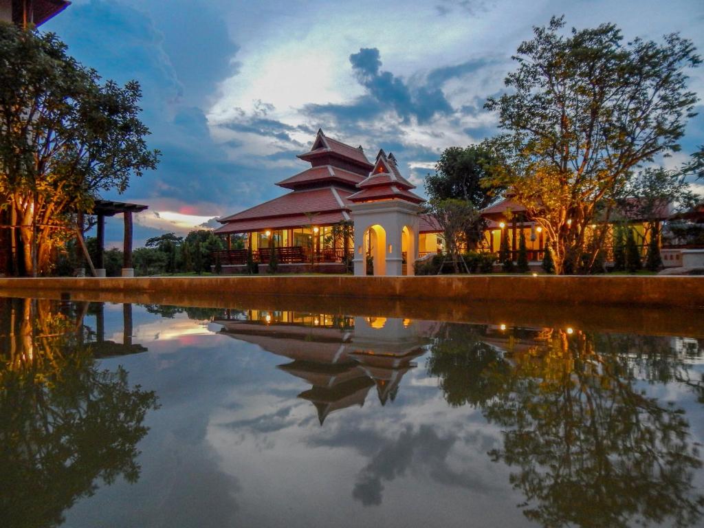 un bâtiment avec une réflexion dans l'eau au crépuscule dans l'établissement Content Villa Chiangmai, à Chiang Mai