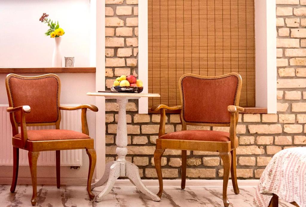 dos sillas sentadas junto a una mesa con un bol de fruta en Old Town cosy one bedroom apartments with fireplace, en Vilna