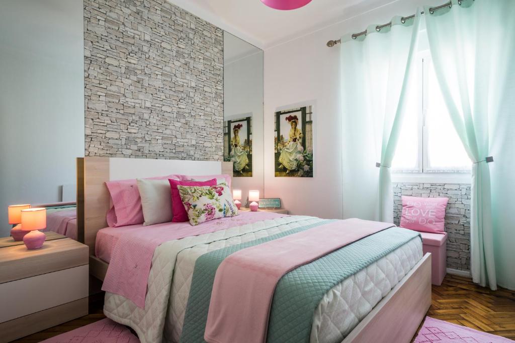 een slaapkamer met een bed met roze en groene lakens bij Dream City Home in Caldas da Rainha