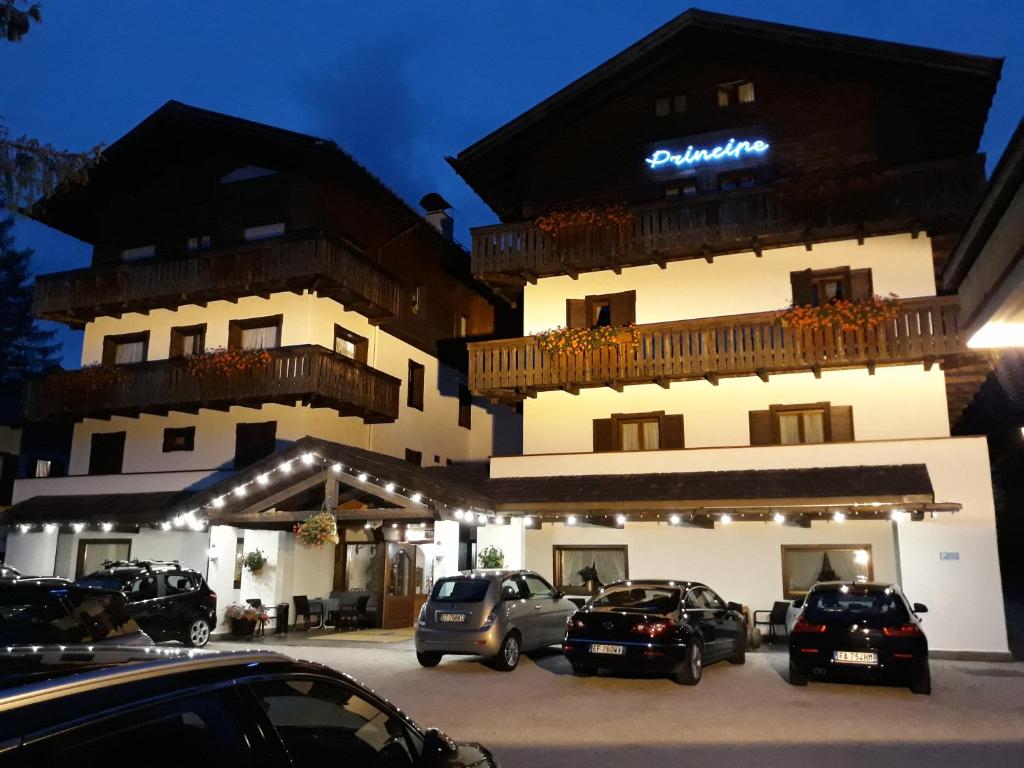 un gran edificio con coches estacionados en un estacionamiento en Hotel Principe, en Cortina dʼAmpezzo