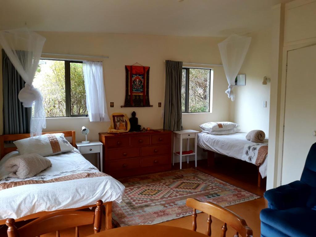 a bedroom with two beds and a dresser and two windows at Mahamudra Buddhist Centre in Colville