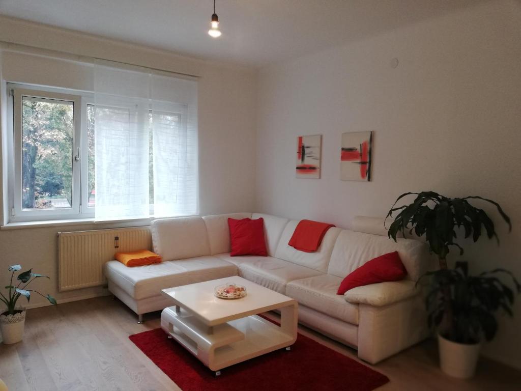 グラーツにあるApartment Meschnikのリビングルーム(白いソファ、赤い枕付)