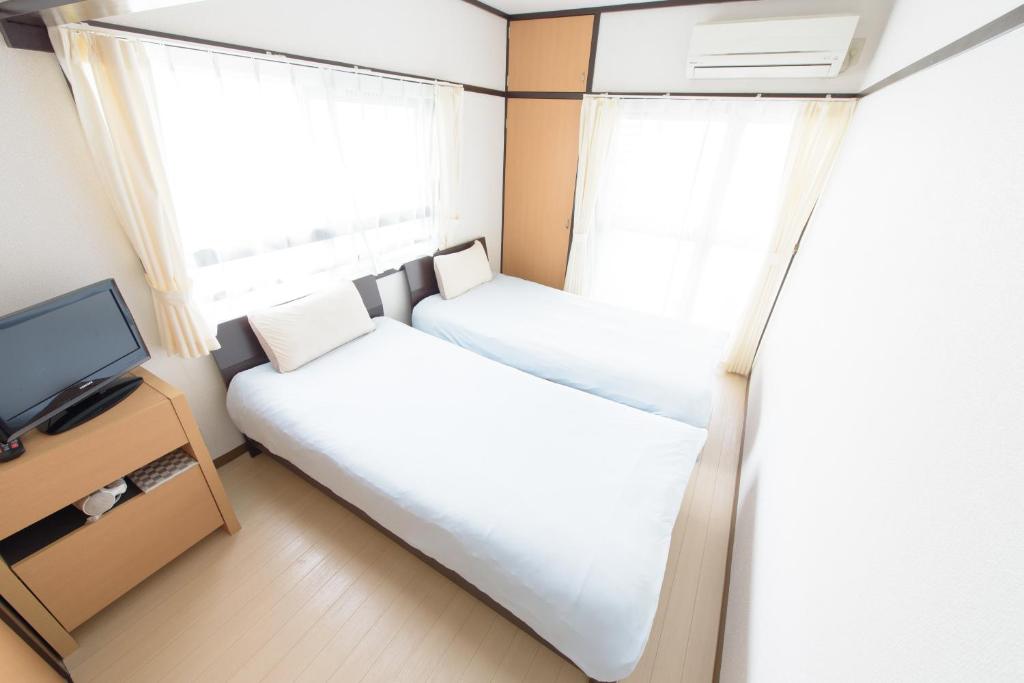 広島市にあるCOCOSTAY Felice ココステイ フェリーチェのベッド2台とテレビが備わる小さな客室です。