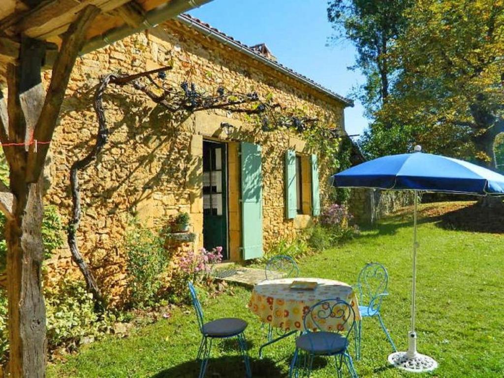 a table and chairs with an umbrella in front of a house at Comfortable holiday home with garden in Sainte-Croix-de-Beaumont
