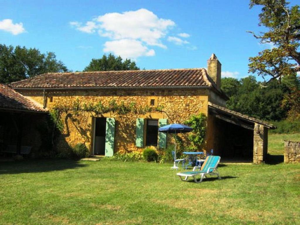 a stone house with two chairs and an umbrella at Comfortable holiday home with garden in Sainte-Croix-de-Beaumont