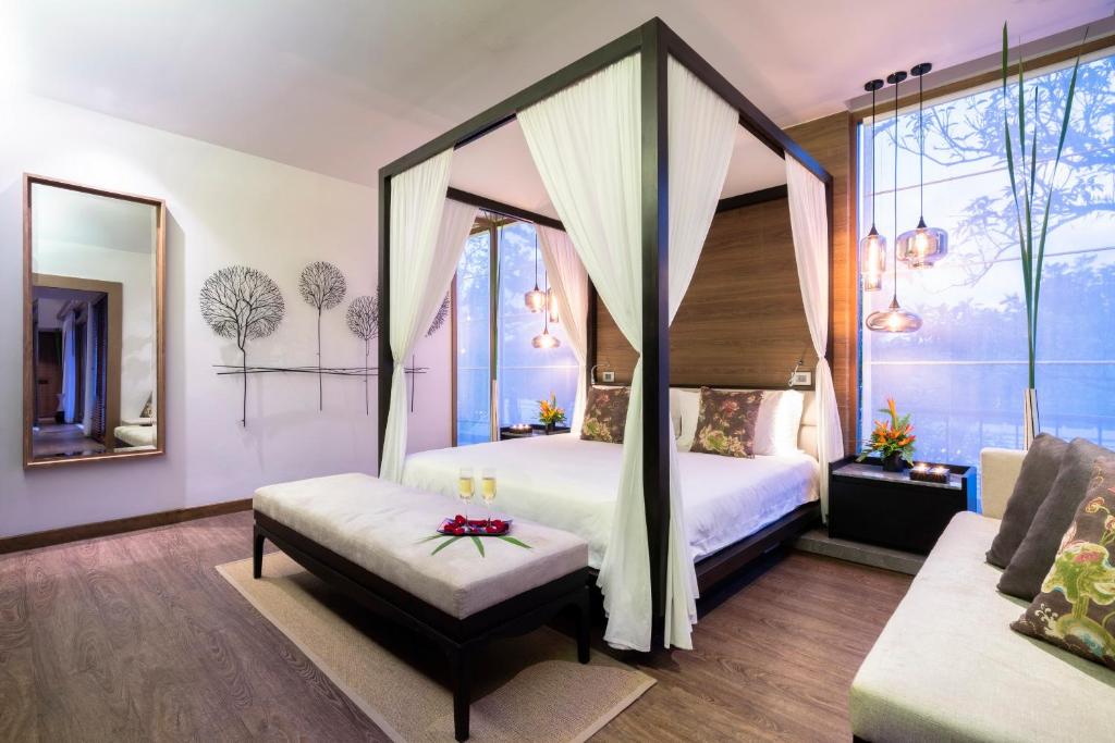 a bedroom with a canopy bed and a couch at The Sarojin in Khao Lak