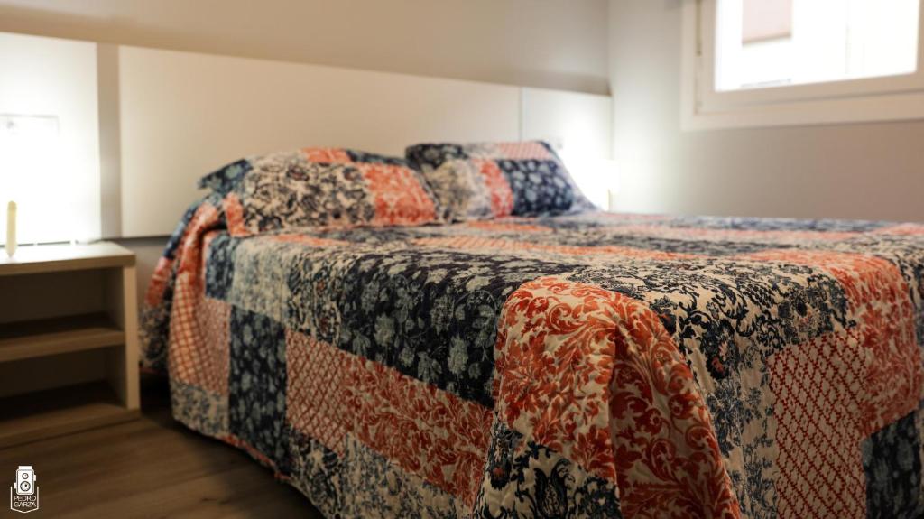 a bedroom with a bed with a quilt on it at dp85 Apartamentos in Sarria
