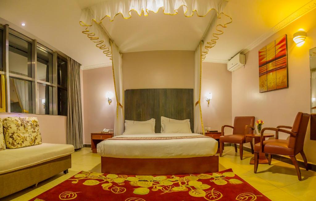 um quarto com uma cama, uma cadeira e uma mesa em Russell Hotel em Kampala