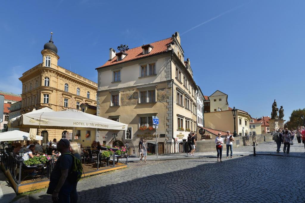 a group of people walking around a street with buildings at Hotel U 3 Pstrosu in Prague