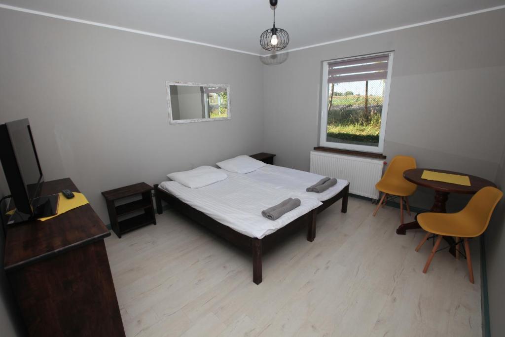 1 Schlafzimmer mit einem Bett, 2 Stühlen und einem Fenster in der Unterkunft Hotelik nad Jeziorem in Łasin