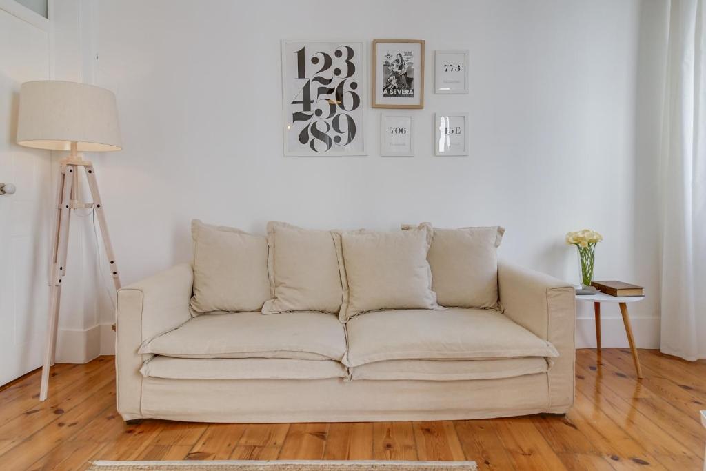 Madragoa Cosy Apartment في لشبونة: أريكة بيضاء في غرفة المعيشة مع مصباح