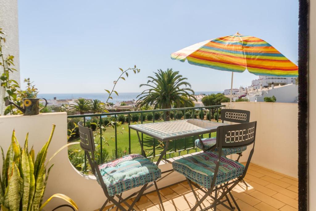 un balcon avec une table, des chaises et un parasol dans l'établissement CHIQUITA PLACE, Praia da Luz, à Luz