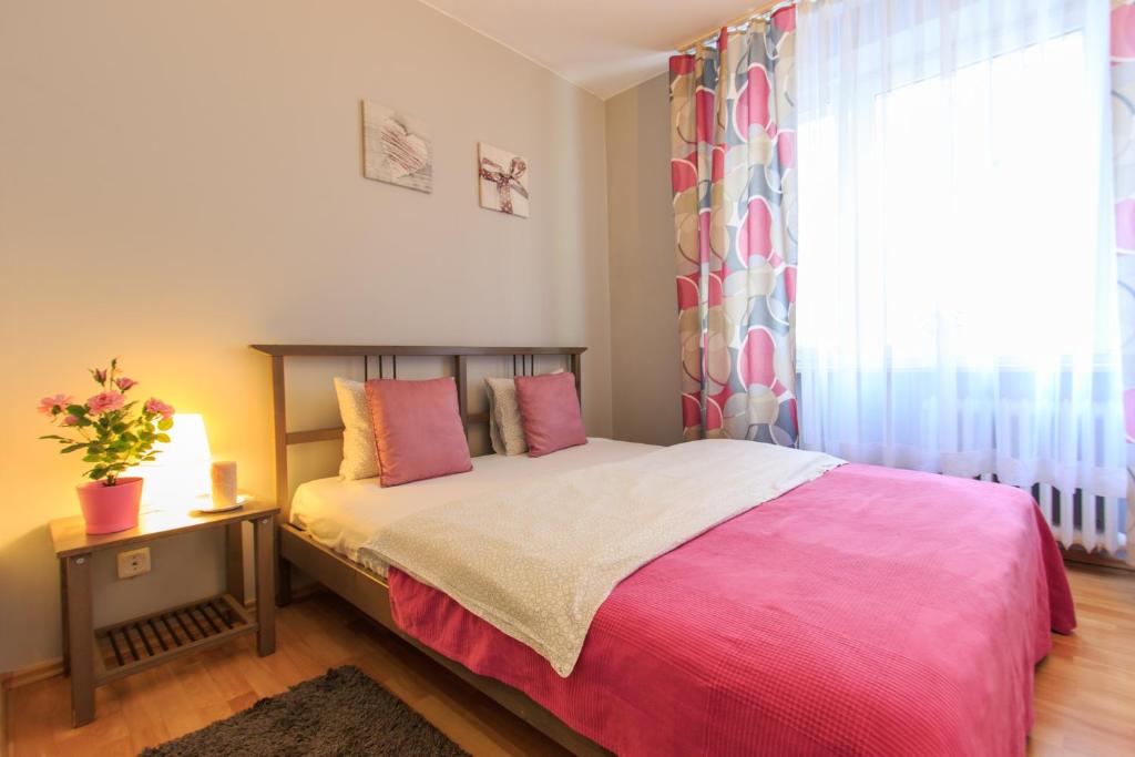 1 dormitorio con 1 cama con manta rosa y ventana en Rental Apartments Warecka, en Varsovia