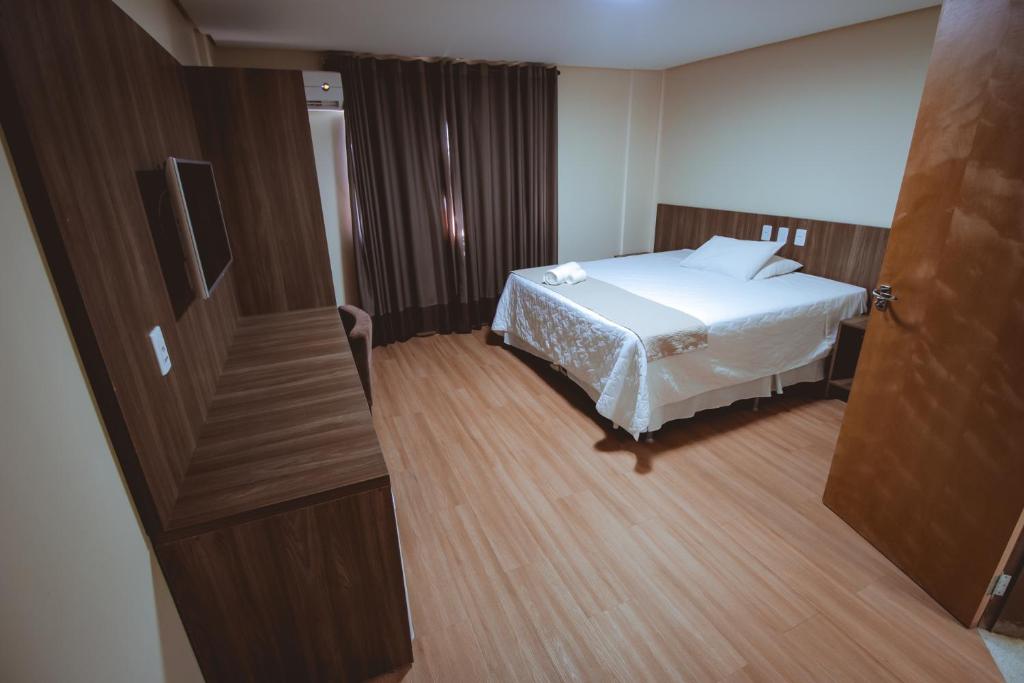 a bedroom with a bed and a wooden floor at Rota Hotéis Mineiros in Mineiros