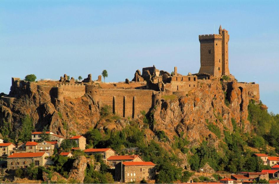 a castle on the side of a mountain with houses at La maison D'Orée in Polignac
