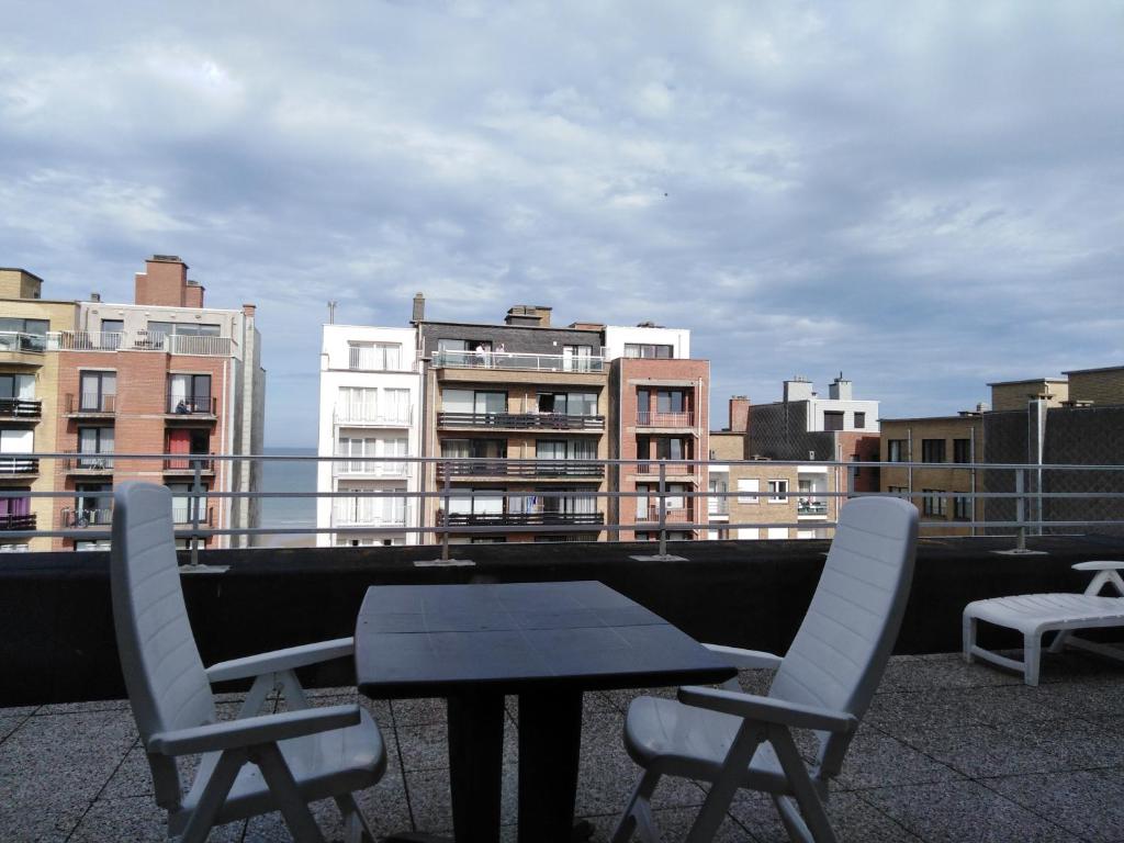 a table and chairs on a balcony with buildings at Dakstudio Met Reuze Zonneterras in Middelkerke