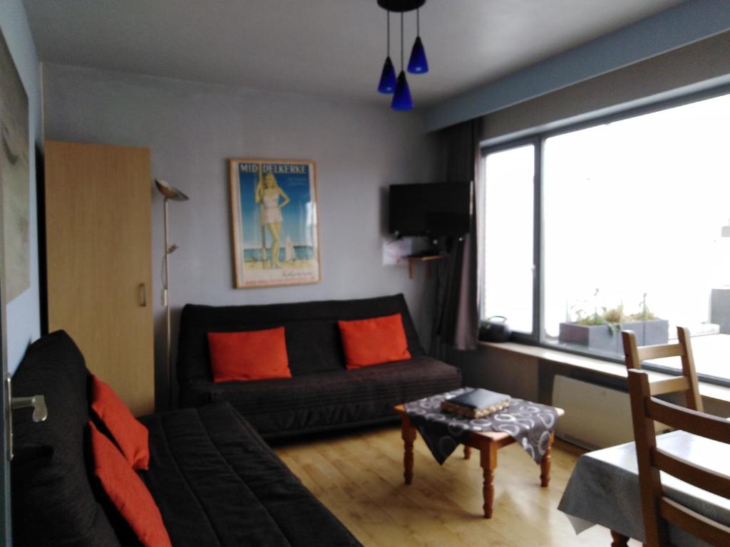 uma sala de estar com um sofá preto e almofadas laranja em Roof Studio with Large Sun Terrace in Middelkerke em Middelkerke