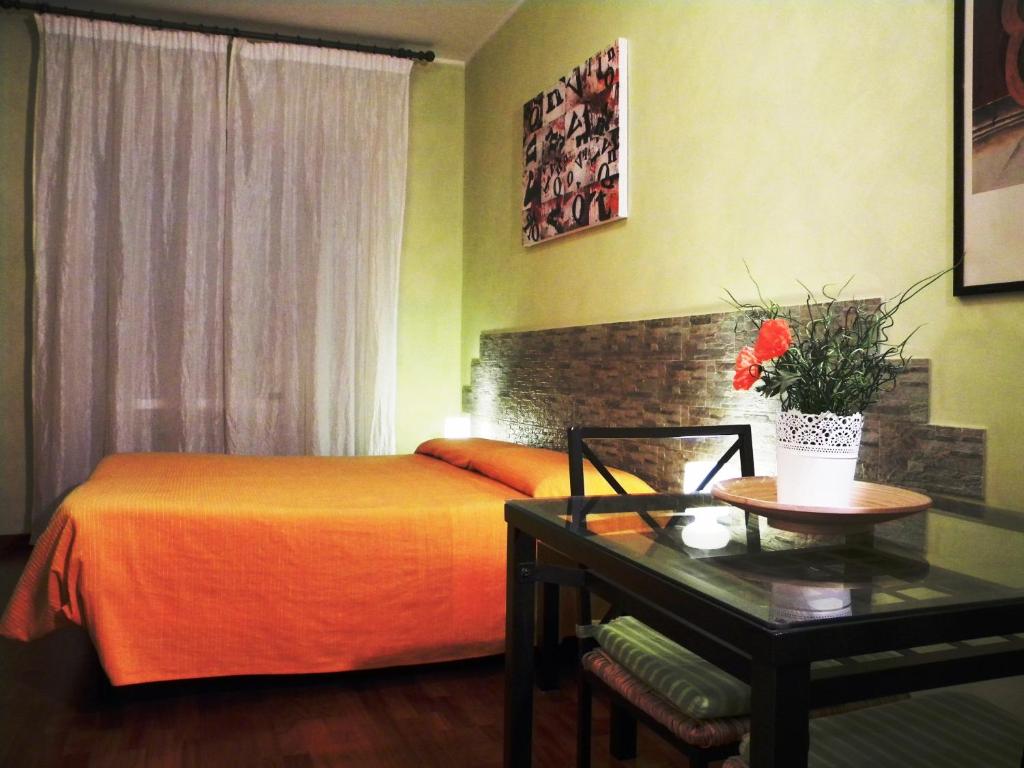 1 dormitorio con 1 cama con colcha de color naranja y mesa en Gregory B&B Vatican, en Roma