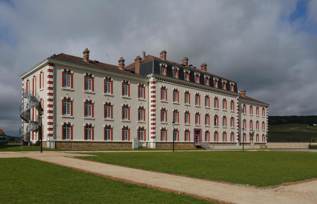 a large white building with a grass field in front at Résidence Vacancéole - Les Demeures Champenoises in Épernay