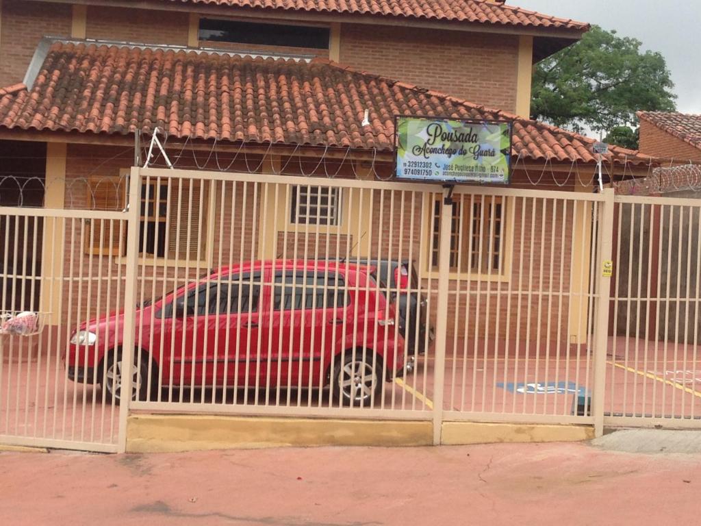 un coche rojo estacionado en un edificio detrás de una puerta en Aconchego do Guara , próximo ao centro médico, Boldrini, Unicamp, Laboratório CNPEN, Universidades e Hospital Sobrapar en Barão de Geraldo