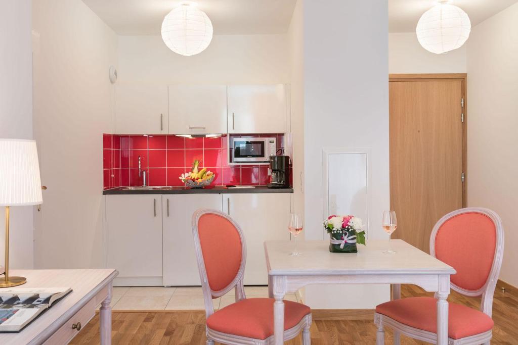 a kitchen with a white table and chairs and red cabinets at Villa Médicis Trouville-sur-mer in Trouville-sur-Mer