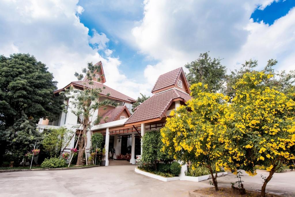 a house with yellow flowering trees in front of it at Wang Yao Riverside Resort in Ban Khlong Bo