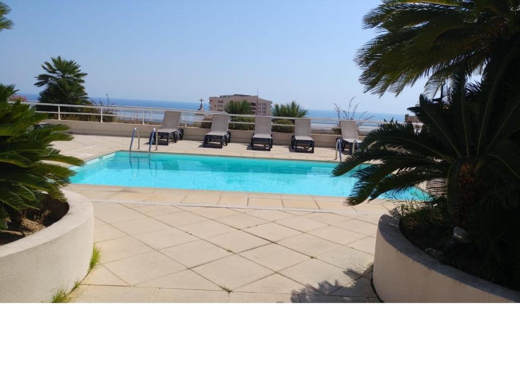 una piscina con sillas y el océano en el fondo en Apartment Monaco Palais Josephine en Beausoleil