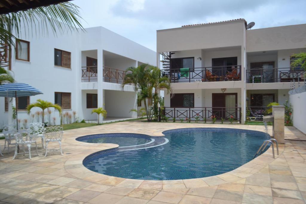 a hotel with a swimming pool in front of a building at Apartamento em Barra do Cunhaú in Barra do Cunhau