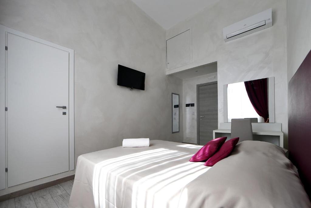 una camera da letto con un grande letto bianco con cuscini rosa di 47 Steps a Roma
