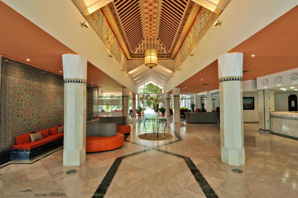eine Lobby eines Hotels mit orangefarbenen Möbeln und einer Decke in der Unterkunft Hôtel Volubilis in Fès