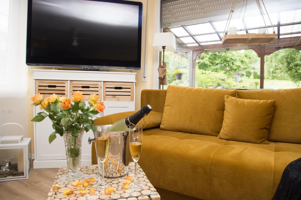 a living room with a yellow couch and a television at Gästehaus Köhler in Waldsolms
