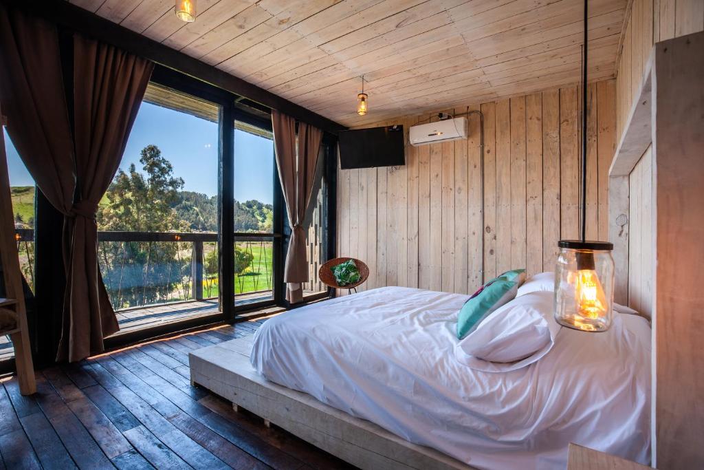 um quarto com uma cama e uma grande janela em Manulodge Matanzas em Matanzas