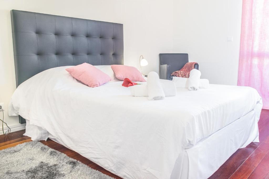 um quarto com uma grande cama branca com almofadas cor-de-rosa em Arcadas Cozy Apartments - AV no Funchal