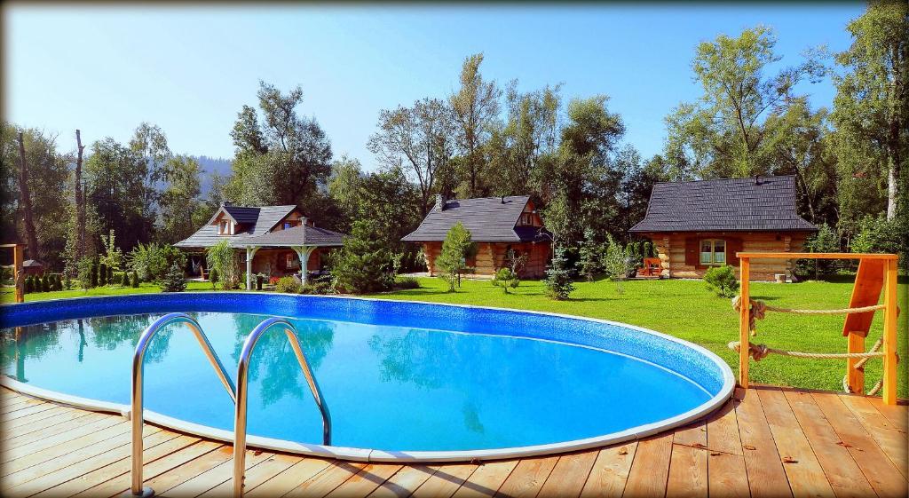 a swimming pool on a wooden deck with a house at Chata w Rabce - Bajkowa Osada in Rabka