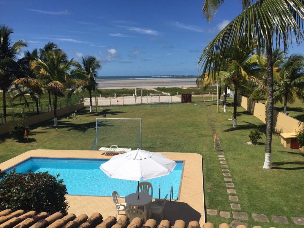 uma piscina com guarda-sol e a praia em Casa Resort em Cacha-Prego
