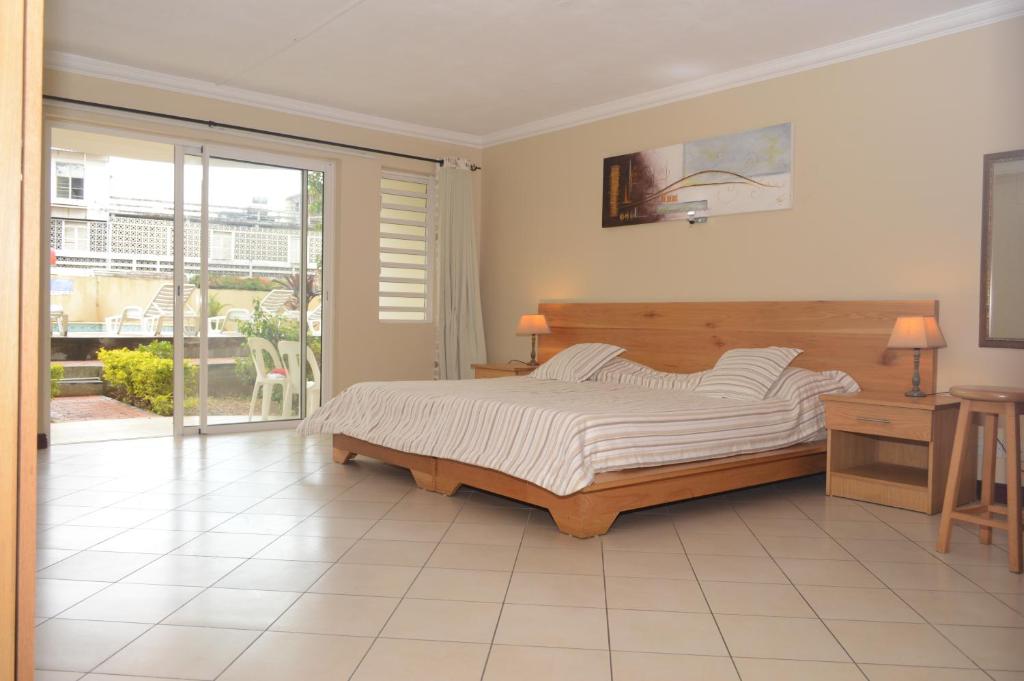 ein Schlafzimmer mit einem großen Bett und einem Fenster in der Unterkunft Résidence Les Peupliers in Flic-en-Flac