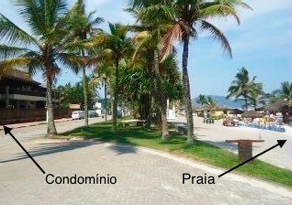 einen Strand mit Palmen und eine Straße mit zwei Pfeilen in der Unterkunft Residências Garcez - Pantai Enseada - Vista Mar in Guarujá