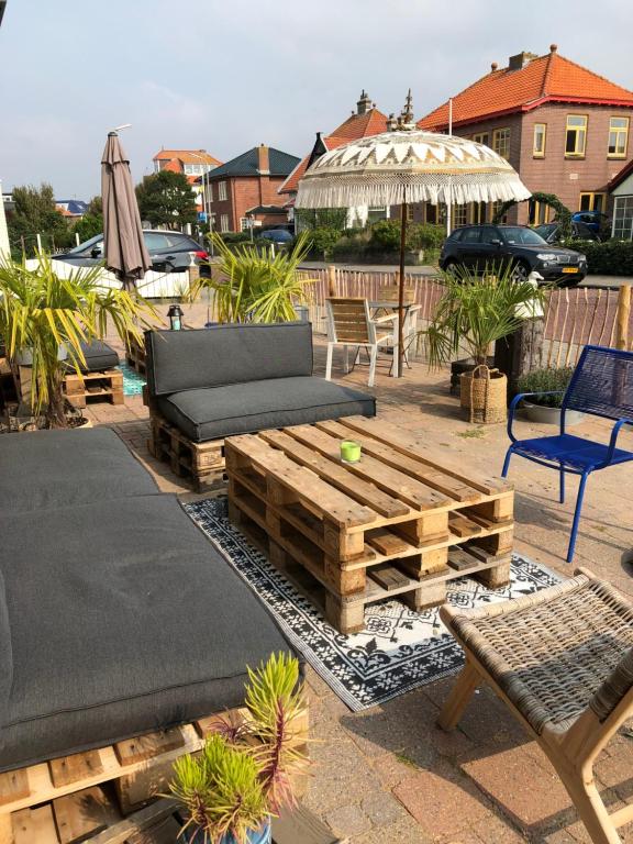 a patio with a couch and a table and an umbrella at Zylt Zandvoort in Zandvoort