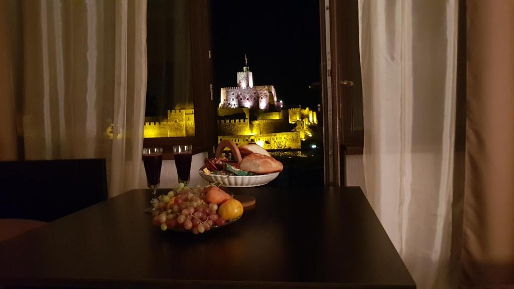 a table with a bowl of fruit and a view of a castle at Hotel Rabati in Akhaltsikhe