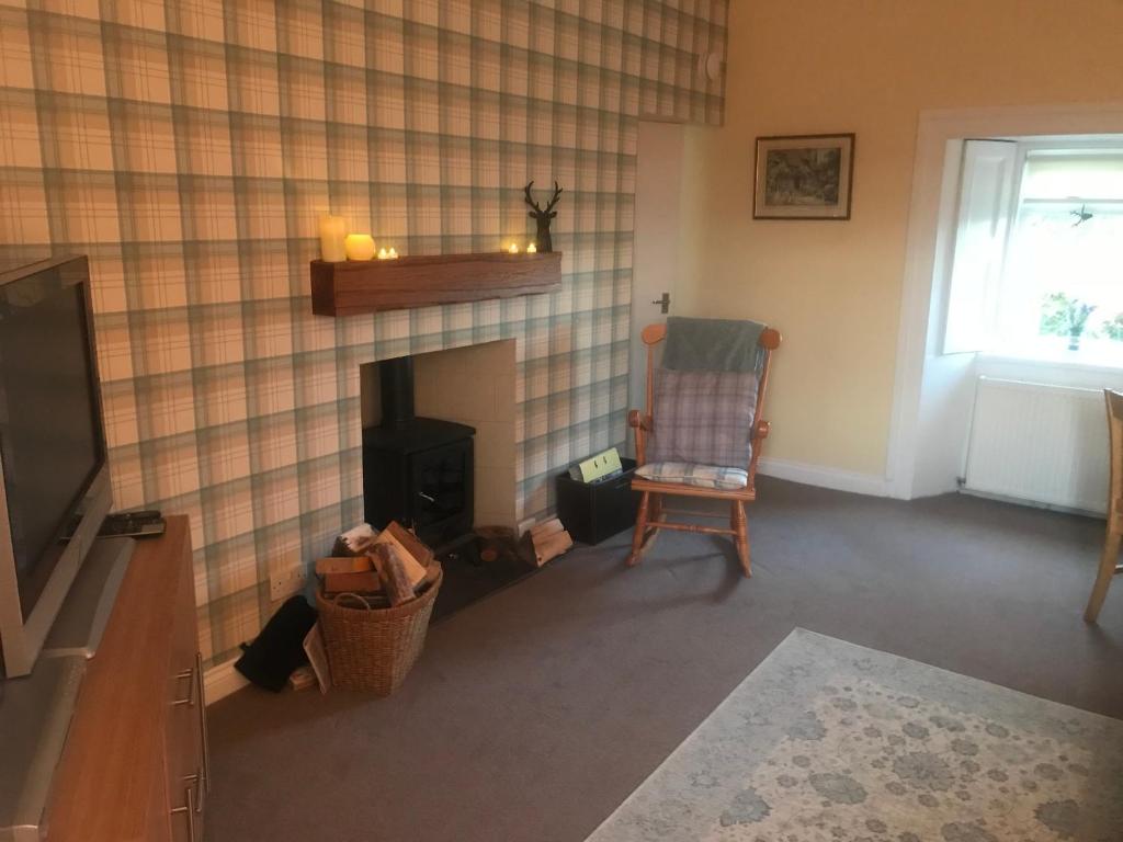 a living room with a fireplace and a chair at Garden Cottage in Gartocharn