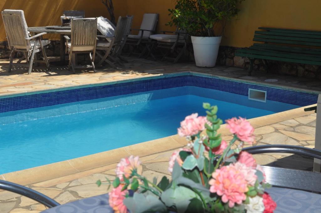 una piscina con una mesa y algunas flores rosas en Pousada Raios do Sol, en Búzios