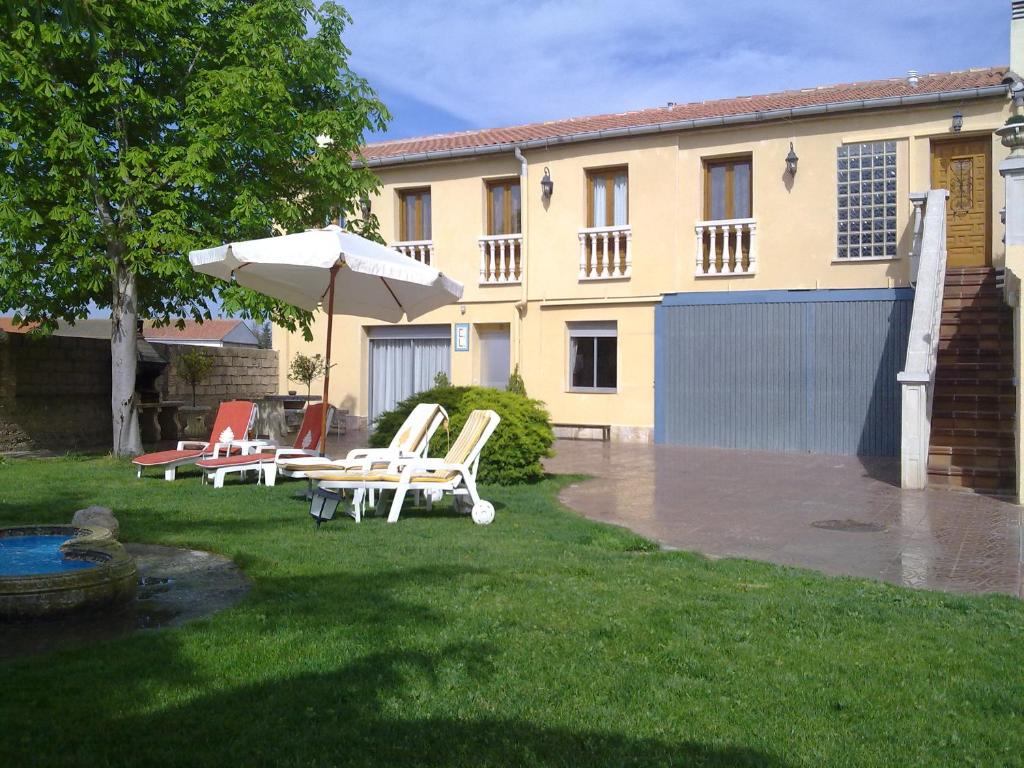 un patio con sillas y sombrilla y un edificio en Casa Rural Sancho el Fuerte en Valtierra