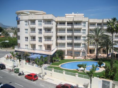 um grande edifício de apartamentos com uma piscina em frente em La Colina em Albir