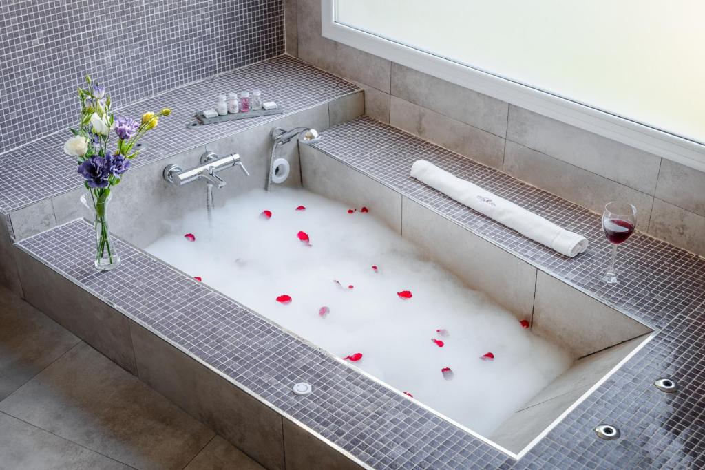 a bath tub filled with red roses and a glass of wine at Villa Mansa in Vistalba
