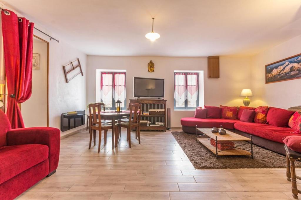 a living room with a red couch and a table at Le Gîte du Lavoir in Marzy