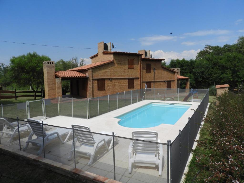 uma piscina com cadeiras e uma casa em CABAÑAS AGUARI em Santa Rosa de Calamuchita