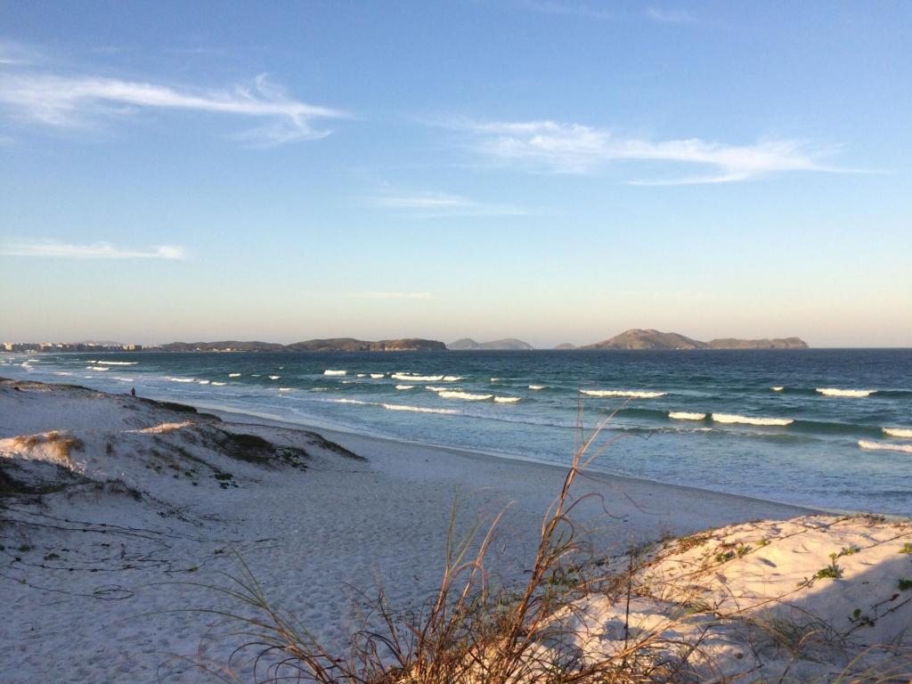 una playa con el océano y las montañas a lo lejos en Banho de Mar em Cabo Frio, en Cabo Frío