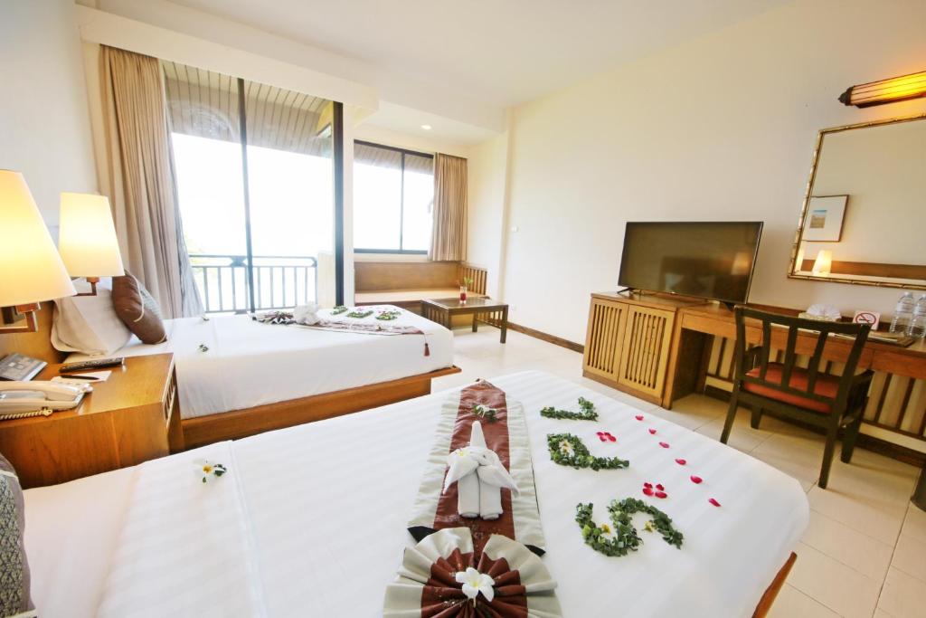 a hotel room with two beds and a flat screen tv at Supalai Scenic Bay Resort And Spa, SHA Extra Plus in Por Bay